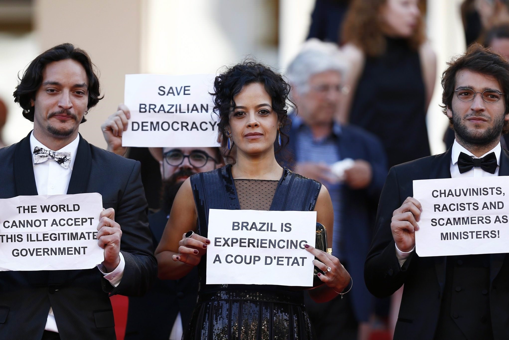 Brazilian actress Maeve Jinkings (C) holds a sign reading 'Brazil is experiencing a coup d'etat' as she leaves after the screening of 'Aquarius' during the 69th annual Cannes Film Festival, in Cannes, France, 17 May 2016. (EPA Photo)