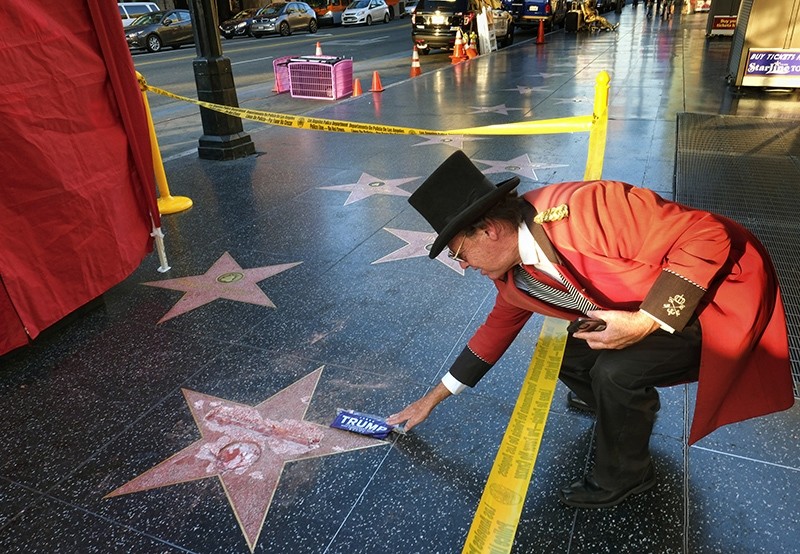 Gregg Donovan, who calls himself the unofficial ambassador of Hollywood, places a sticker for Republican presidential candidate Donald Trump on Trump's vandalized star on the Hollywood Walk of Fame. (AP Photo)