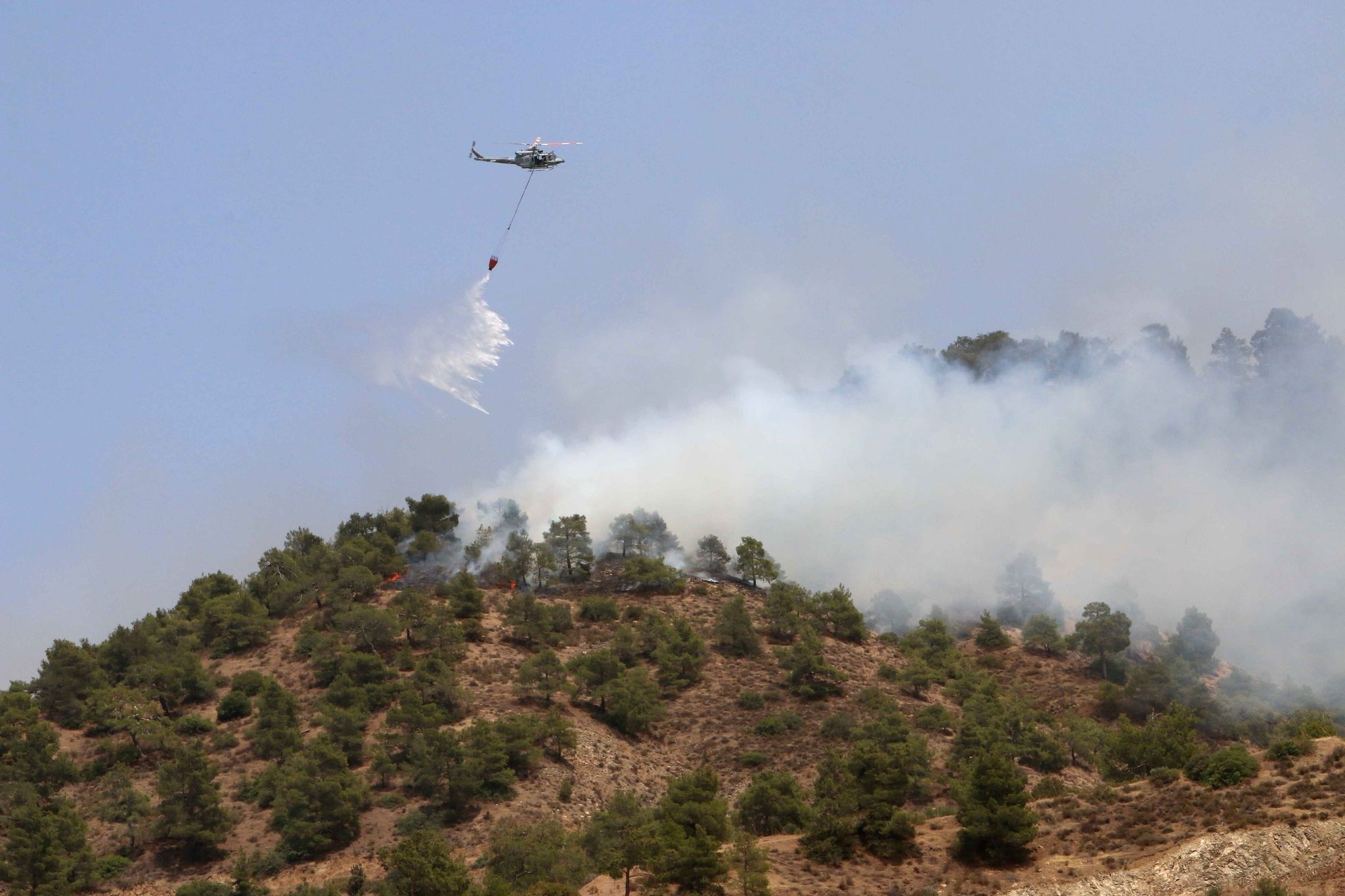 A helicopter drops water on a forest fire in the Cypriot village of Eyrixou in the Trodos mountain area on June 20, 2016. (AFP Photo)