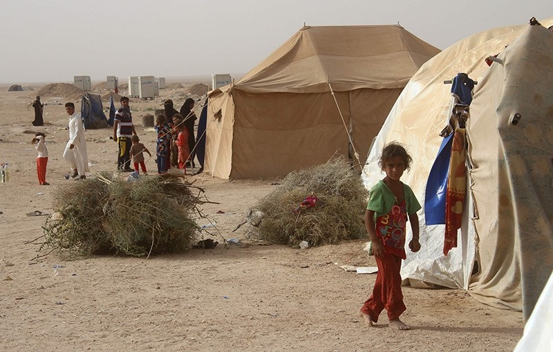 Displaced Iraqis from the embattled city of Fallujah stand outside tents where they are taking shelter some 18 kilometres from Ramadi on June 18, 2016. (AFP Photo)