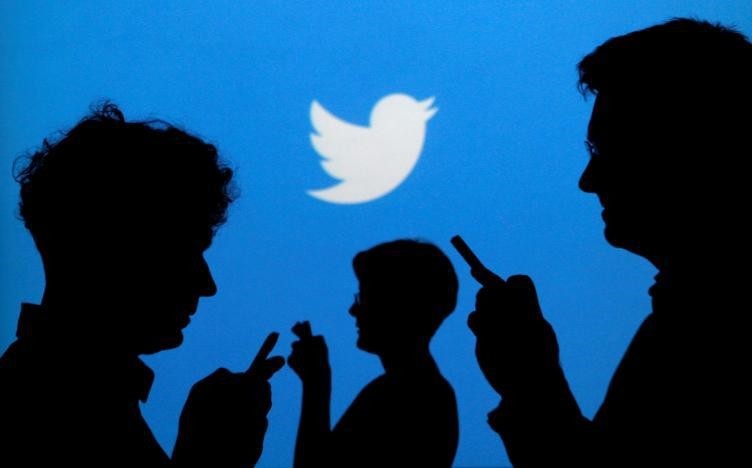 People holding mobile phones are silhouetted against a backdrop projected with the Twitter logo in this illustration picture taken in Warsaw September 27, 2013. (REUTERS Photo)