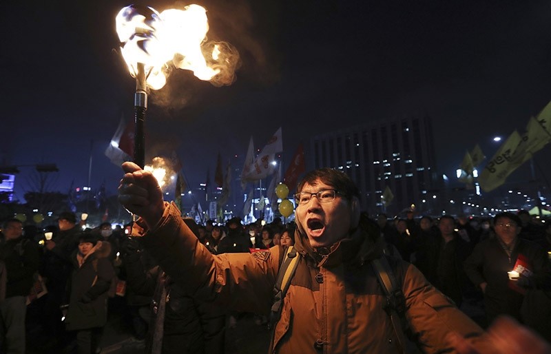 A protester carries a torch with other protesters after a rally against the impeached South Korean President Park Geun-hye in downtown Seoul, South Korea, Saturday, Dec. 17, 2016. (AP Photo)