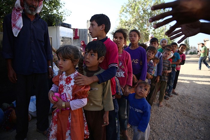 Syrian children, who fled with their families from the village of Hawsh Nasri in Duma, queue to receive aid from an NGO in the village of Shaffuniya in Ghouta, east of the capital Damascus, on August 13, 2016. (AFP Photo)