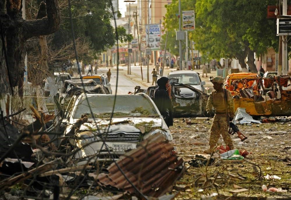 A woman stands next to a soldier at the scene of a terrorist attack on the Ambassador Hotel, which was claimed by Somalia's Al-Qaida-linked al-Shabaab, in Mogadishu on June 2.
