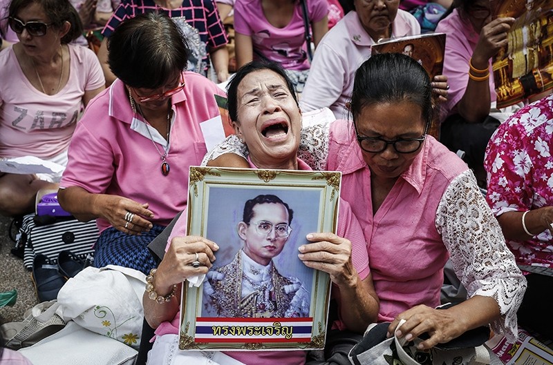 A Thai well-wisher weeps as she is comforted by others during a prayer for Thai King Bhumibol Adulyadej's recovery at the Siriraj Hospital in Bangkok, Thailand (EPA Photo)