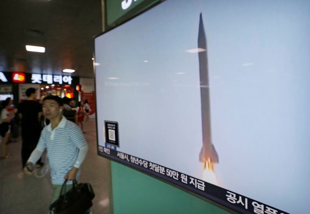 A man passes by a TV news program with file footage of a North Korean rocket launch at the Seoul Railway Station in Seoul, South Korea, Wednesday, Aug. 3, 2016. (AP Photo)