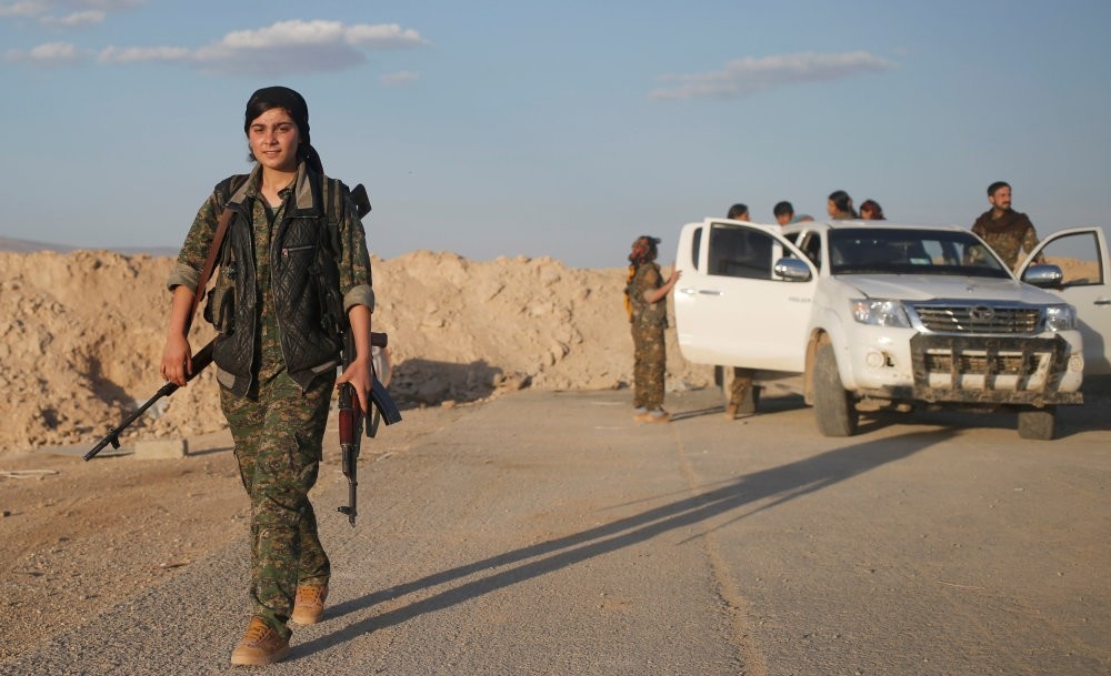 A female member of the Sinjar Resistance Units (YBS), a militia affiliated with the PKK, carrying a sniper and an AK-47 rifle in the village of Umm al-Dhiban, Northern Iraq.