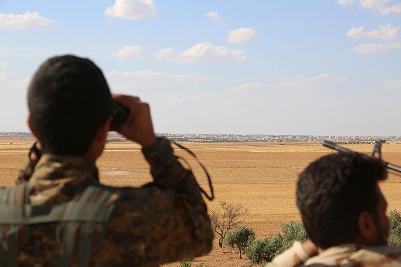 Fighters from the Syrian Democratic Forces (SDF) use binoculars from a view point overlooking the northern Syrian town of Manbij held by Daesh terrorists. (AFP Photo)