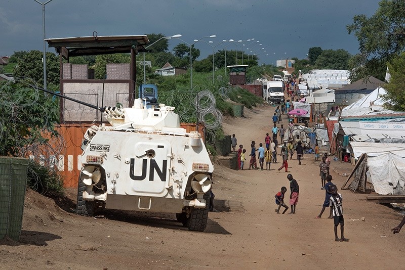 Some of the more than 30,000 Nuer civilians sheltering in a UN base in South Sudan's capital Juba for fear of targeted killings by gov't forces walk by an armored vehicle and a watchtower manned by Chinese peacekeepers, July 25, 2016. (AP Photo)