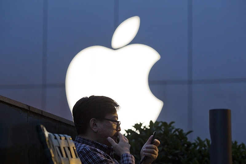 In this Friday, May 13, 2016, file photo, a man uses his mobile phone near an Apple store in Beijing. (AP Photo)
