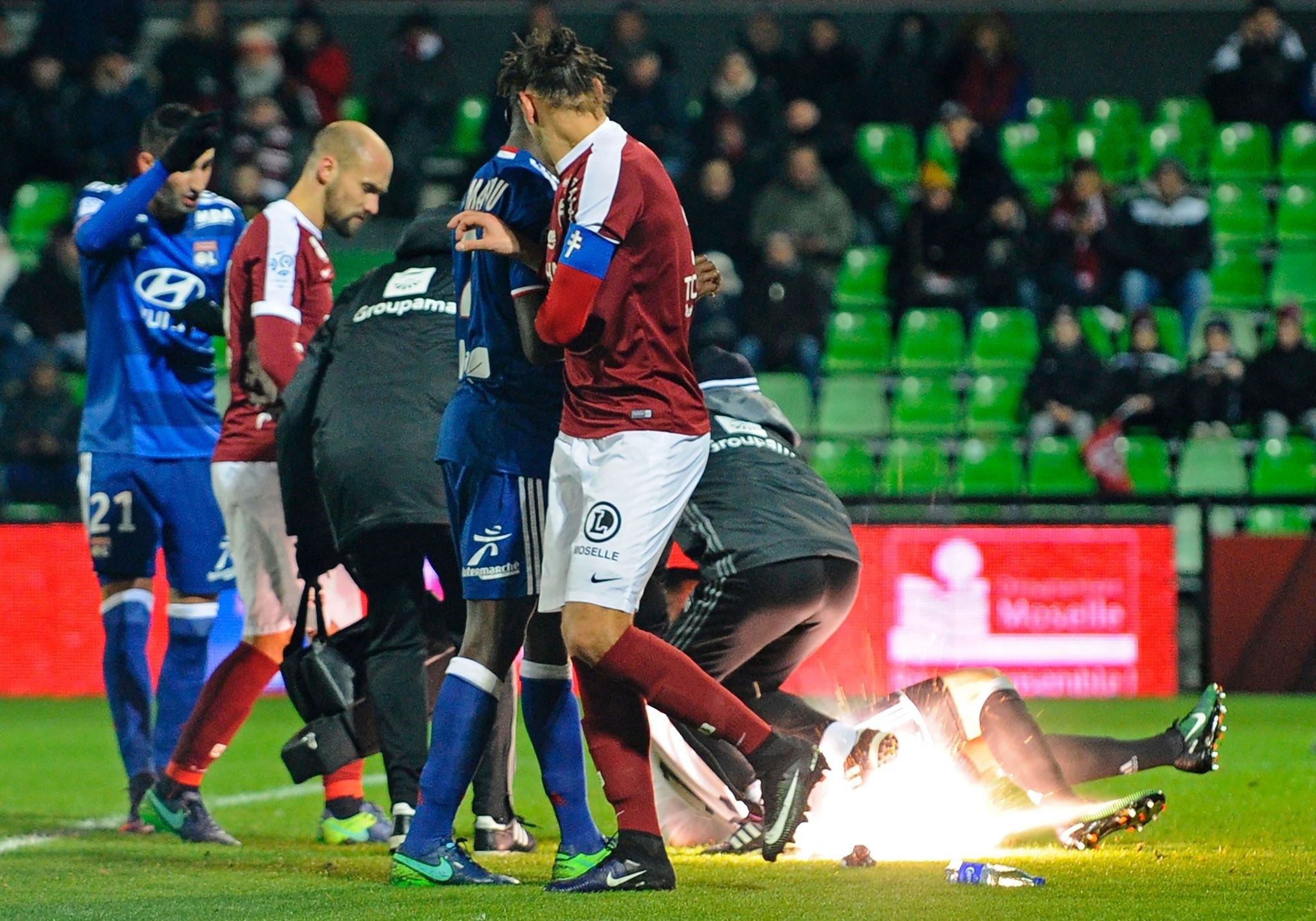 A firecracker explodes beside Lyon and Metz players during the French L1 football match between Metz (FCM) and Lyon (OL) on December 3, 2016. (AFP Photo)
