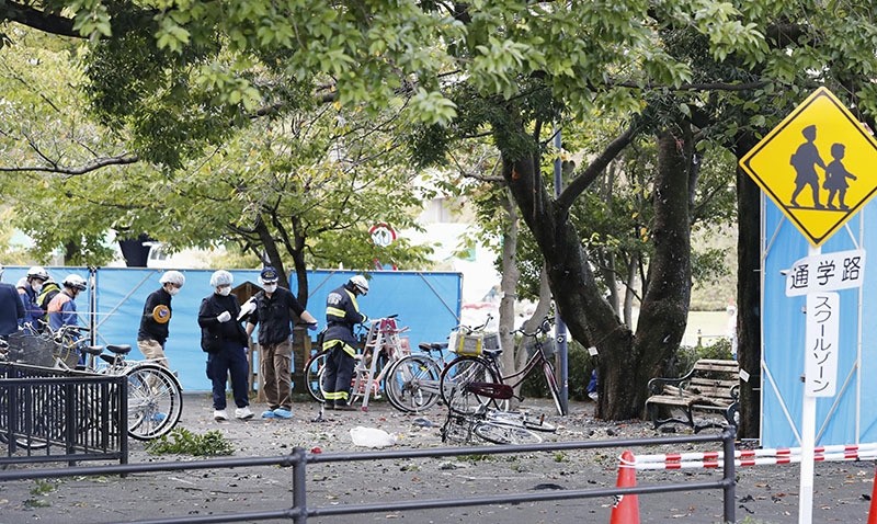 Police officers investigate near a damaged wooden bench, right, following an explosion at a park in Utsunomiya, north of Tokyo, Sunday, Oct. 23, 2016. (AP Photo)