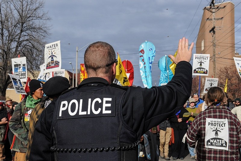 A police officer stands guard as people march during a protest against plans to pass the Dakota Access pipeline near the Standing Rock Indian Reservation, North Dakota, U.S. November 14, 2016. (Reuters Photo)