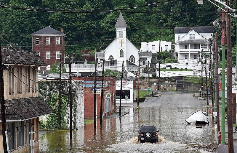A vehicle makes a wake along the flooded Lower Oakford Ave. Friday, June 24, 2016, in Richwood, W.Va.  Archive Photo