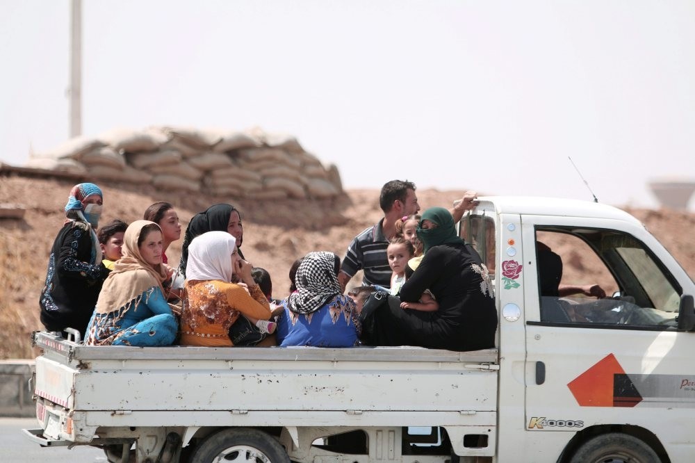 People ride on the back of a pickup truck as they flee Hasakah, Syria, Aug. 20.
