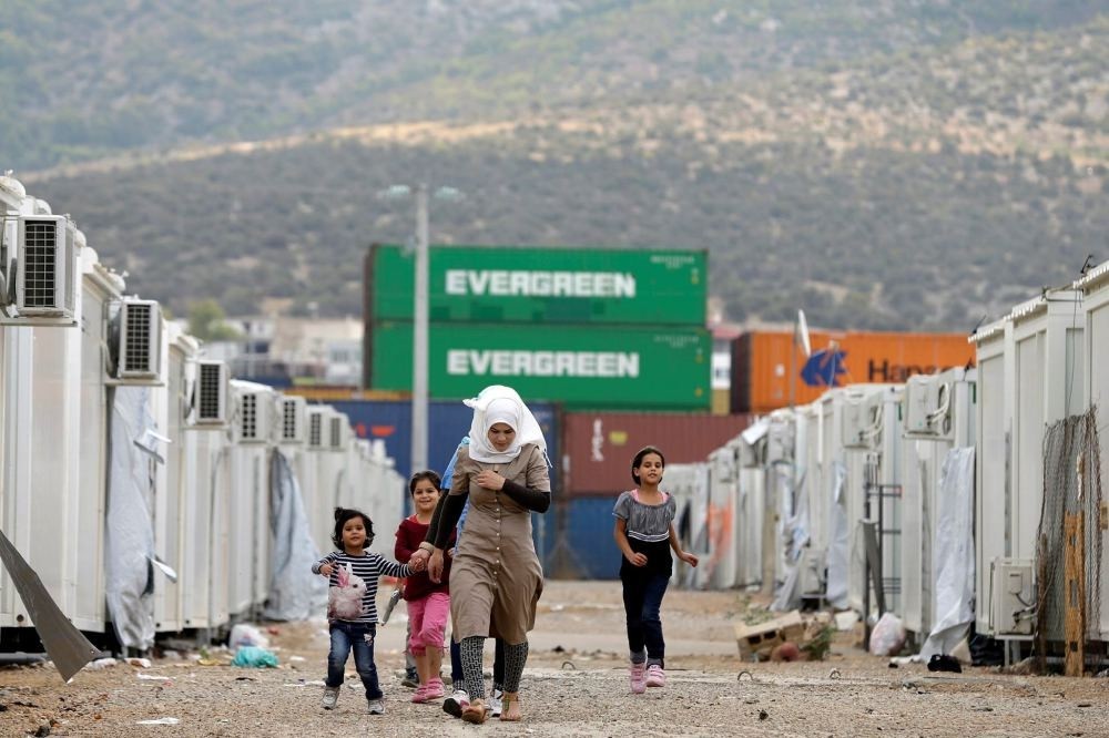 People walk at a refugee camp which houses about 3,200 refugees, in the western Athens' suburb of Skaramagas, Greece.
