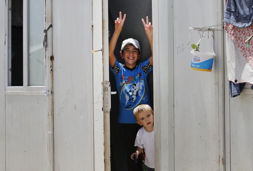 A Syrian boy showing the v sign from a container at the u00d6ncu00fcpu0131nar camp for Syrian refugees in the Kilis province of Turkey.
