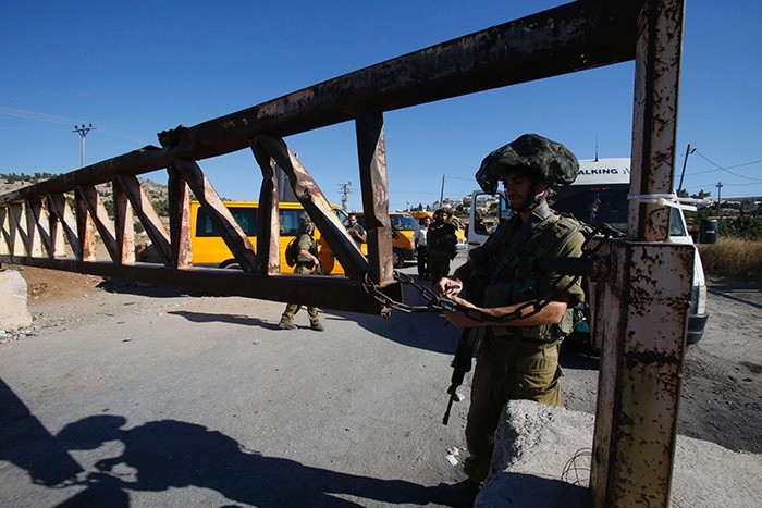 Israeli soldiers open a barrier blocking access to the al-Fawwar refugee camp, south of the West Bank city of Hebron, on July 26, 2016. (AFP Photo)