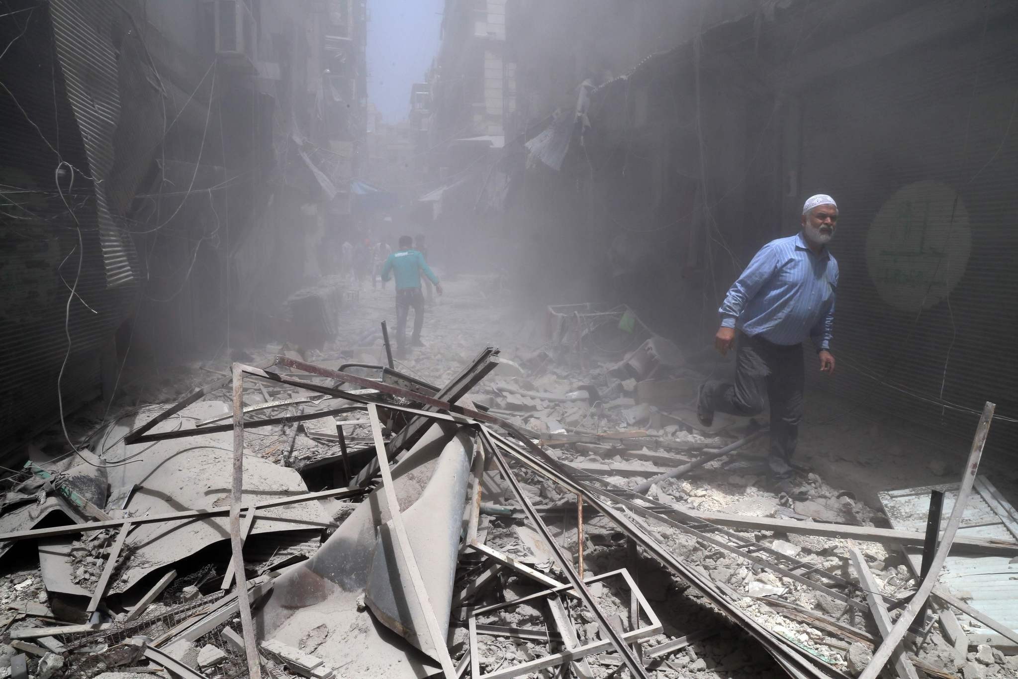 Syrians walk through the rubble following a reported air strike by Syrian regime forces in the opposition-held neighbourhood of Bustan al-Qasr on June 5, 2016. (AFP PHOTO)