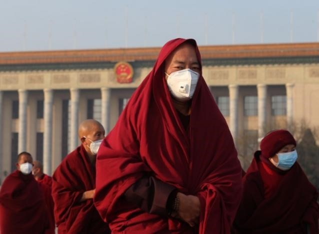 Monks wearing masks walk at Tiananmen Square during a polluted day in Beijing.