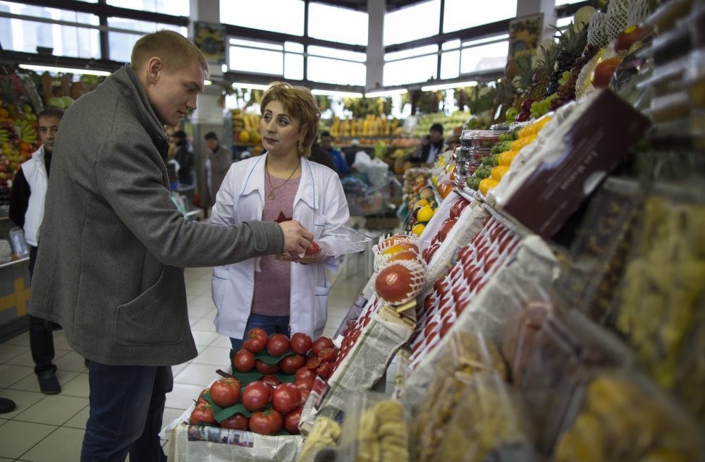 A merchant helps a customer buy tomatoes at Dorogomilovsky food market in Moscow. Since Turkey shot down Russian plane that violated its airspace, Russia has restricted tourism, left Turkish trucks stranded at border and confiscated imports.
