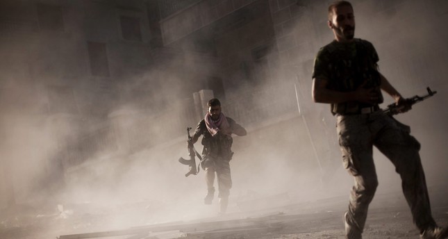 Two rebel Free Syrian Army soldiers run after attacking a Syrian Army tank during fighting in the Izaa district in Aleppo, Syria. (AP Photo)