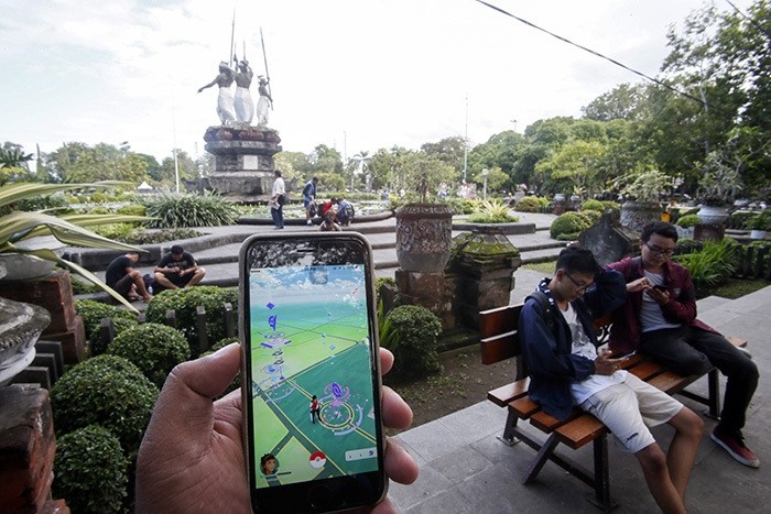 A person plays with Pokemon Go on his mobile phone at a park in Denpasar, Bali, Indonesia, 20 July 2016. (EPA Photo)