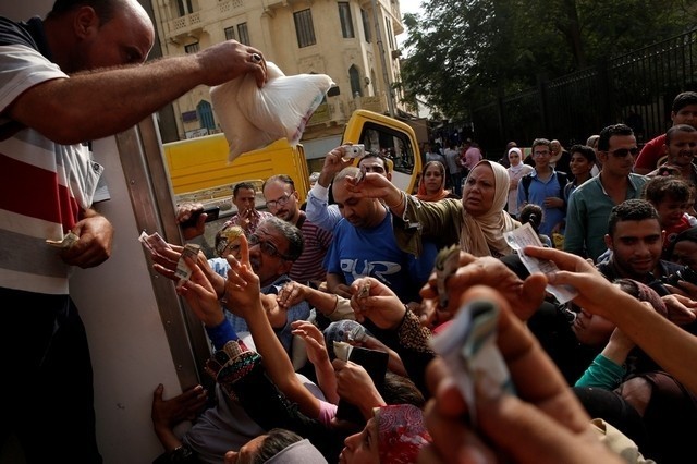 A policeman tries with other Egyptians to buy subsidised sugar from a government truck after a sugar shortage in retail stores across the country in Cairo, Egypt. (Reuters Photo)