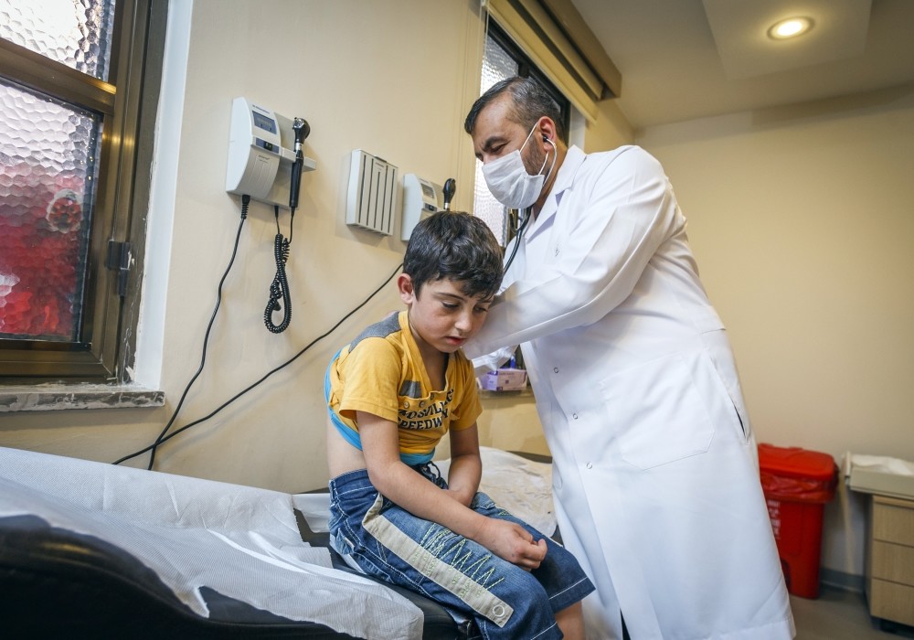 Zakaria Sallan examines Ibrahim, a 9-year-old refugee boy.