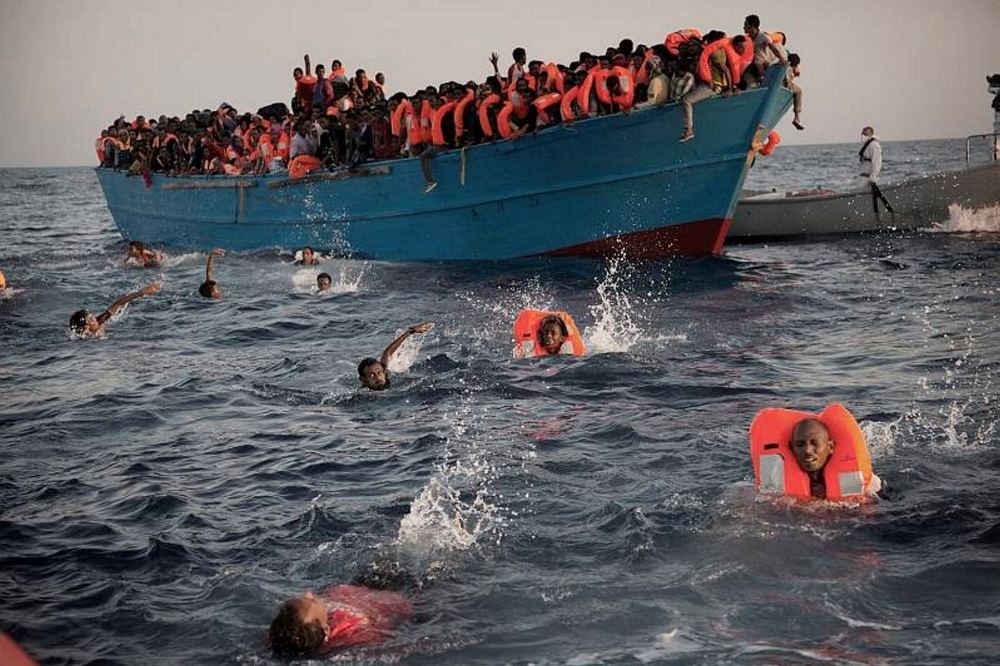 Migrants, most of them from Eritrea, jump into the water from a crowded wooden boat as they are helped by members of an NGO during a rescue operation at the Mediterranean sea, about 13 miles north of Sabratha, Libya, Aug. 29.