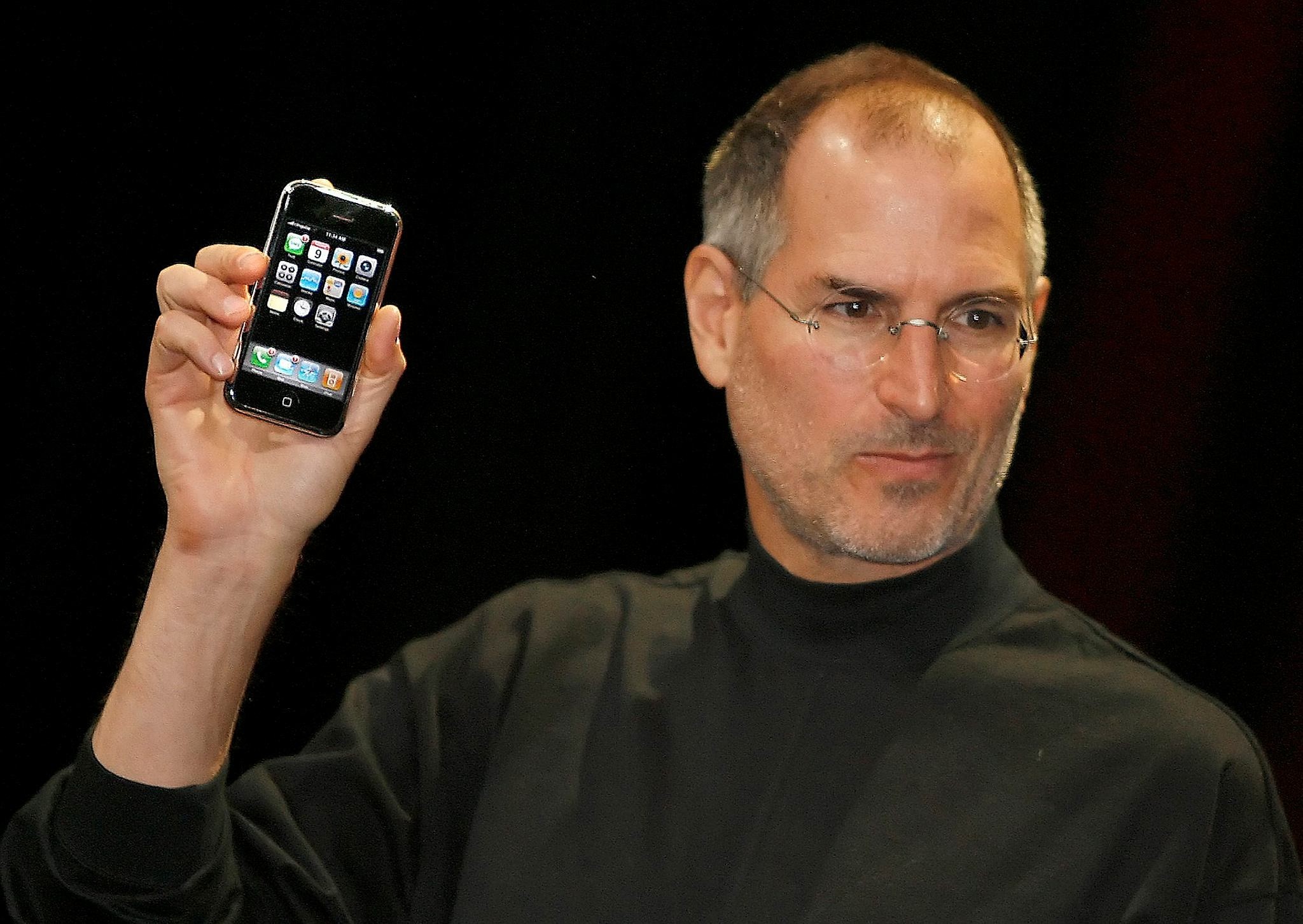 Late Apple founder Steve Jobs holds the very first iPhone (AFP Photo)