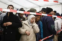 In this file photo taken on Oct. 15, 2015, refugees wait in exclusion zone for transport to a registration office at the State Office of Health and Welfare in Berlin (AP)