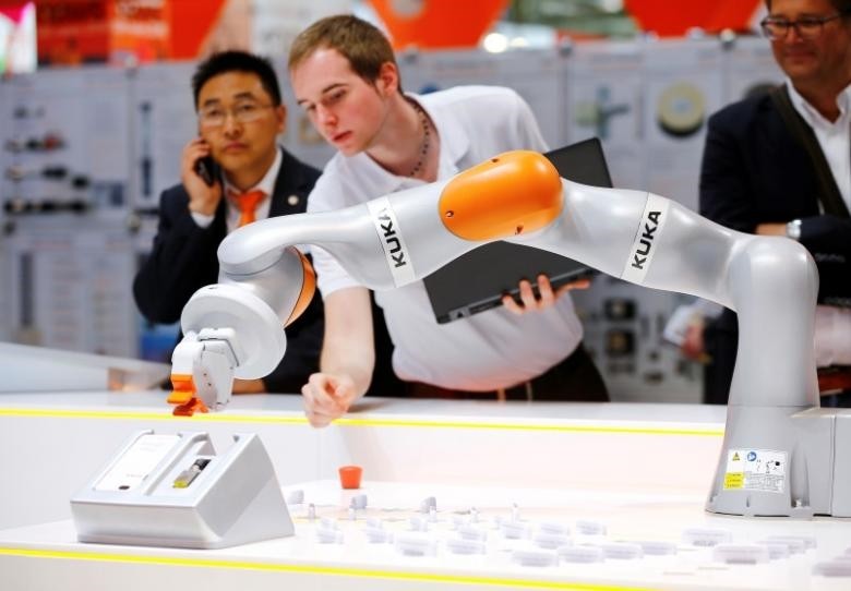A technician programs a robot arm of German industrial robot maker Kuka at the companyu2019s stand during the Hannover Fair in Hanover.