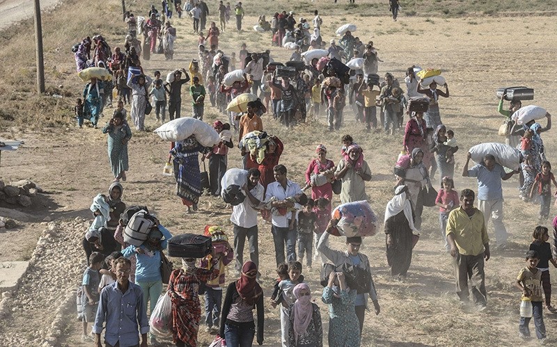 Syrians carry their belongings after crossing into Turkey near the southeastern town of Suruu00e7 in u015eanlu0131urfa province, on September 19, 2014 (AFP Photo)