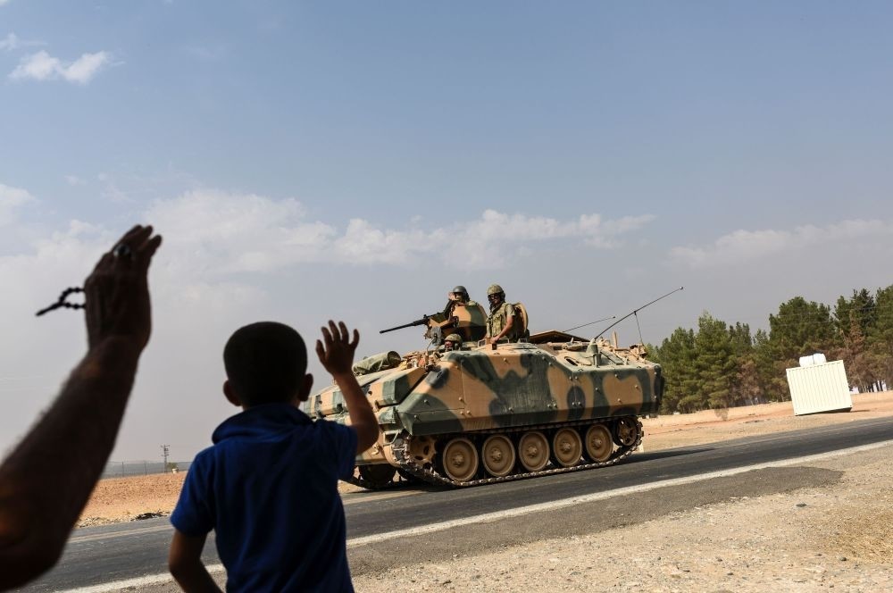 A boy waving to Turkish tank convoy driving into Syria from the Karkamu0131u015f distrcit in Turkey's southern province of Gaziantep on the border wtih Syria, on Aug. 26.