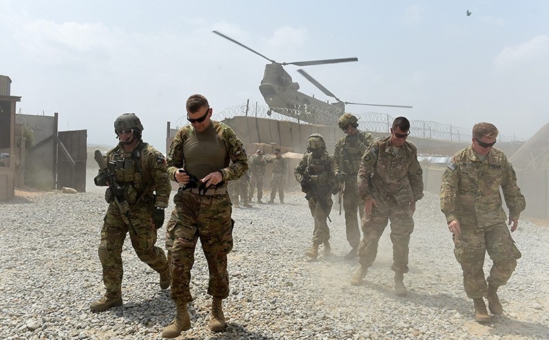 In this photograph taken on August 13, 2015, US army soldiers walk as a NATO helicopter flies overhead at coalition force Forward Operating Base (AFP Photo)