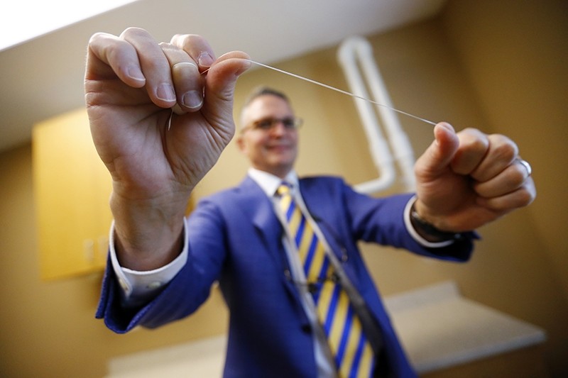 Dr. Wayne Aldredge, president of the American Academy of Periodontology, holds a piece of dental floss at his office in Holmdel, N.J. (AP Photo)