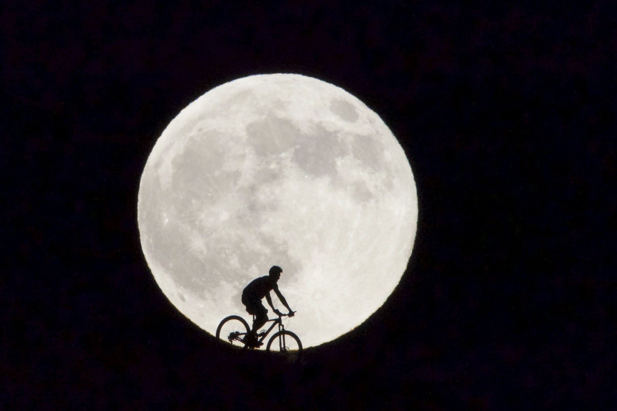  A cyclist is seen passing before the supermoon in Fuerteventura, Canary Islands, Spain, 29 August 2015. (EPA Photo)