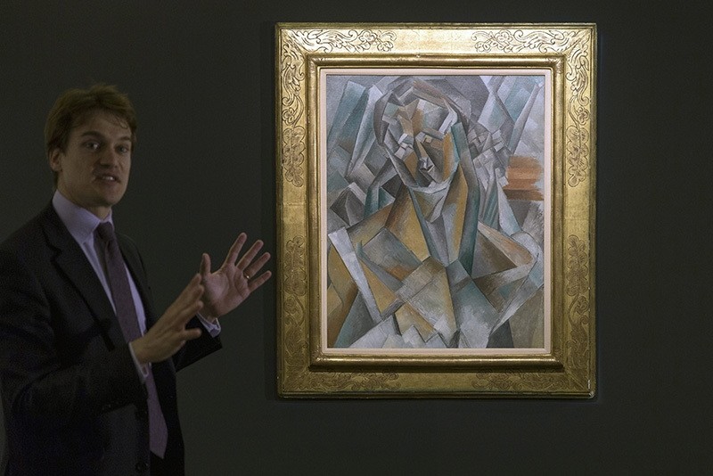 Simon Stock, Sotheby's senior director, senior international specialist, impressionist and modern art, unveils Picasso's 'Femme Assise' during a media preview at Sotheby's in Hong Kong, China, May 27, 2016. (AP Photo)