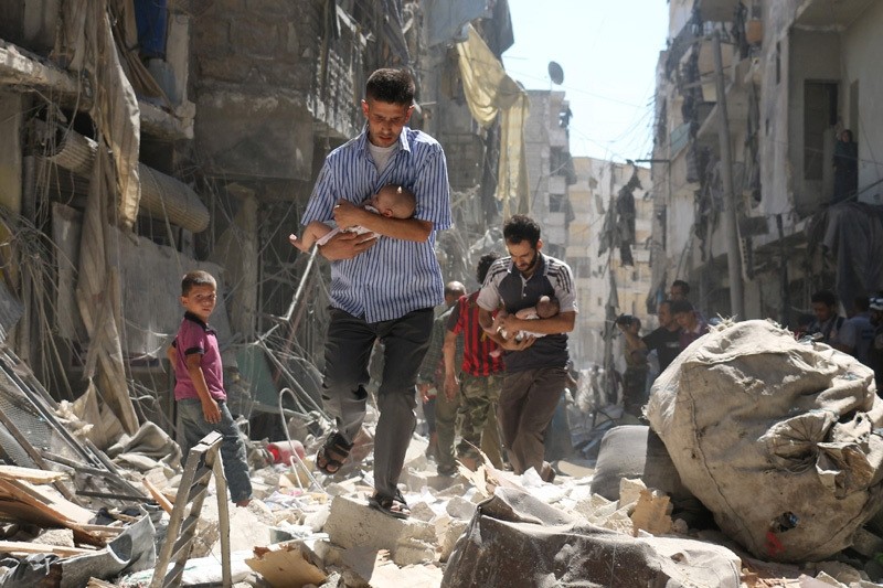 Syrian men carrying babies make their way through the rubble of destroyed buildings following a reported airstrike on the opposition-held Salihin neighbourhood of the northern city of Aleppo, on September 11, 2016.  AFP Photo