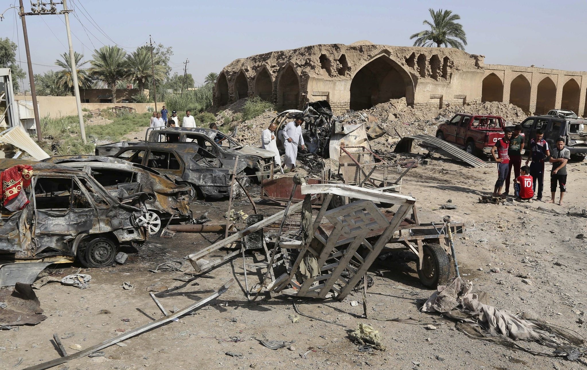 Civilians inspect the scene of a deadly friday night suicide car bombing at a busy market in Khan Beni saad, about 20 miles (30 kilometers) northeast of Baghdad, Iraq, Saturday, July 18, 2015. (AP Photo)