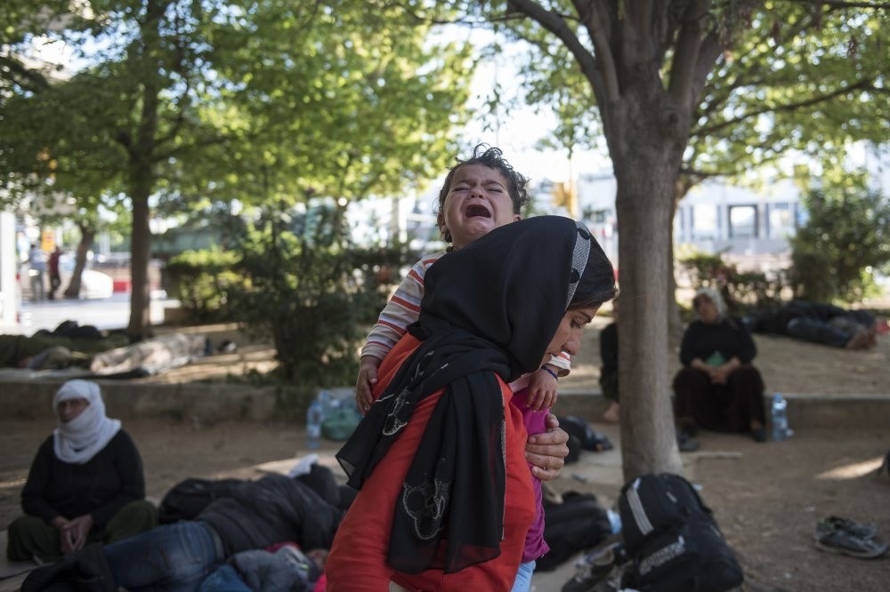 A woman carries her crying baby in a park in the northern Greek city of Thessaloniki, July 9.