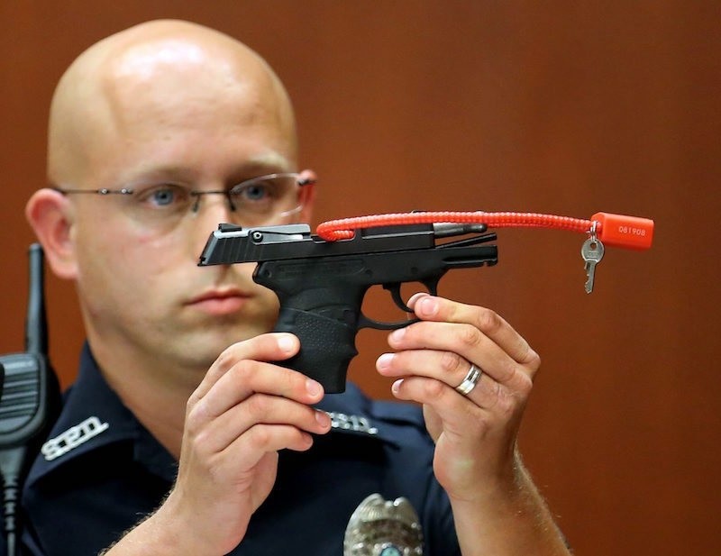 Sanford police officer Timothy Smith holds up the gun that was used to kill Trayvon Martin, while testifying in the George Zimmerman trial. (AP Archive Photo)