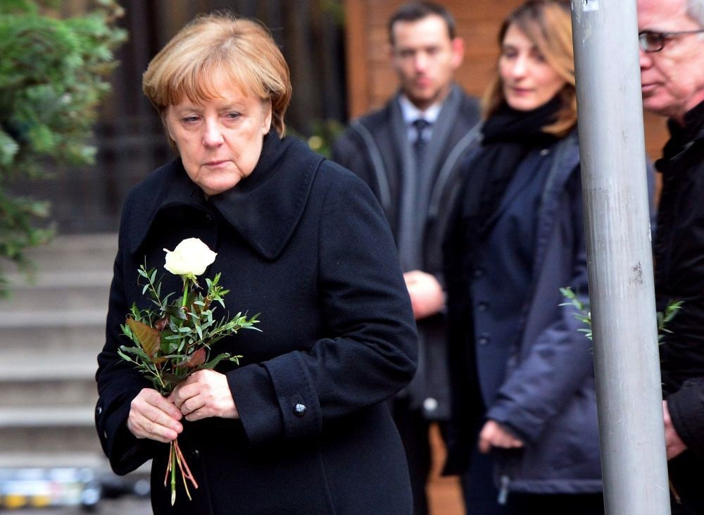 German Chancellor Angela Merkel lays flowers with German Interior Minister Thomas de Maiziere on Dec. 20 at the site where a truck crashed into a Christmas market near the Kaiser-Wilhelm-Gedaechtniskirche.