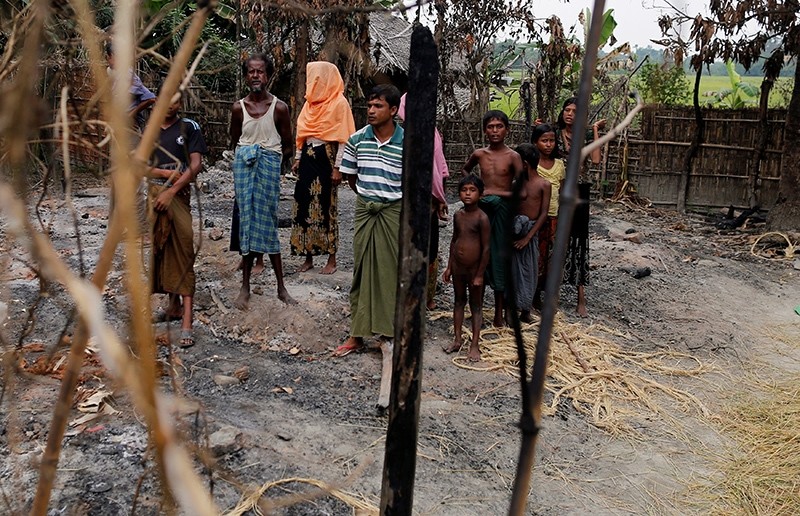 A family stands beside remains of a market, which was set on fire in Rohingya village, outside Maungdaw in Rakhine state, Myanmar October 27, 2016. (Reuters Photo)