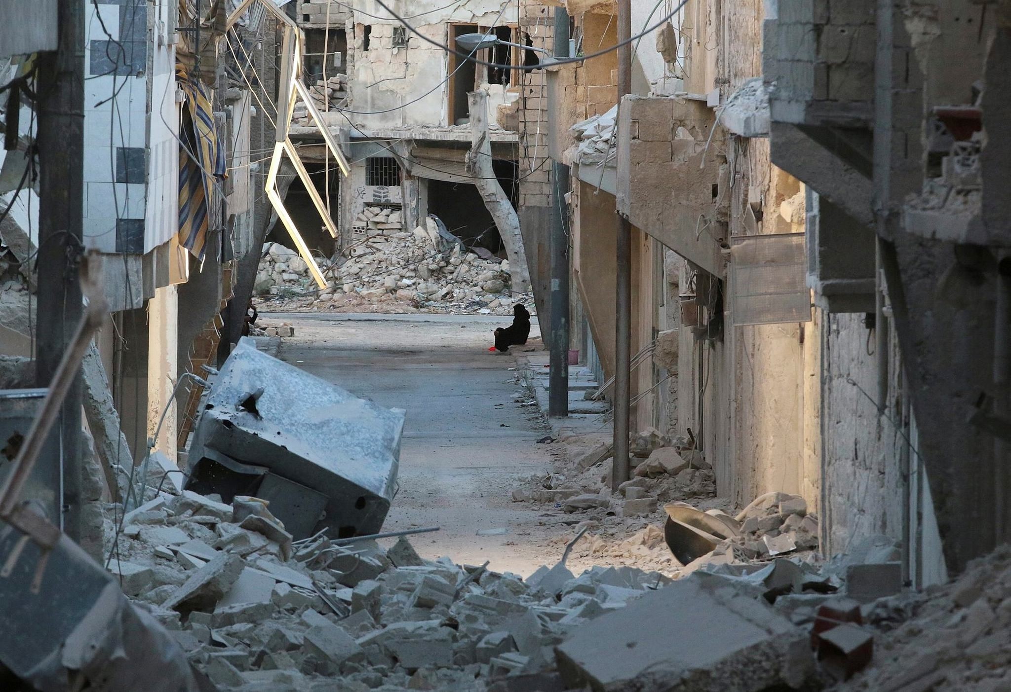 A woman sits amid damaged buildings in the opposition-held al-Myassar neighborhood of Aleppo, Syria, Sept. 27.