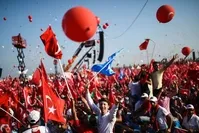 People waving flags as they stand in front of giant screens next to balloons in the color of the Turkish national flag in Istanbul at the Democracy and Martyrs Rally against the July 15 coup attempt, Aug. 7.