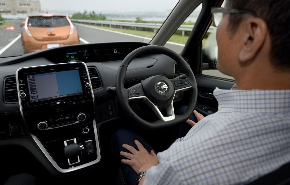 A journalist sitting in the driveru2019s seat of the all-new minivan Serena from Japanese auto giant Nissan Motor takes his hands off the steering wheel during a test drive, at the test course of the companyu2019s Oppama plant in Yokohsuka.