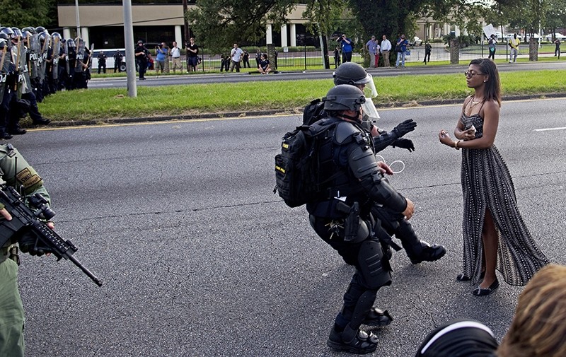 In this Saturday, July 9, 2016 file photo, A protester is grabbed by police officers in riot gear after she refused to leave the motor way in front of the the Baton Rouge Police Department Headquarters in Baton Rouge, La. (AP Photo)