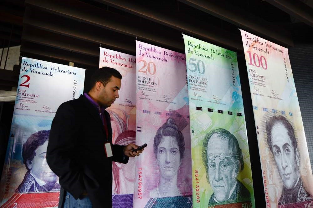 A man walks past banners showing Venezuelau2019s currency, the bolivar, at the Central Bank of Venezuela in Caracas.